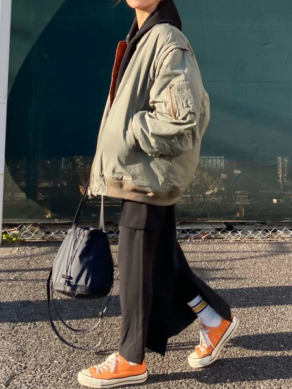 ブラック系のスカート、グリーン系のMA-1、ブラック系のパーカーを着用したレディースの春コーディネートの3枚目の写真