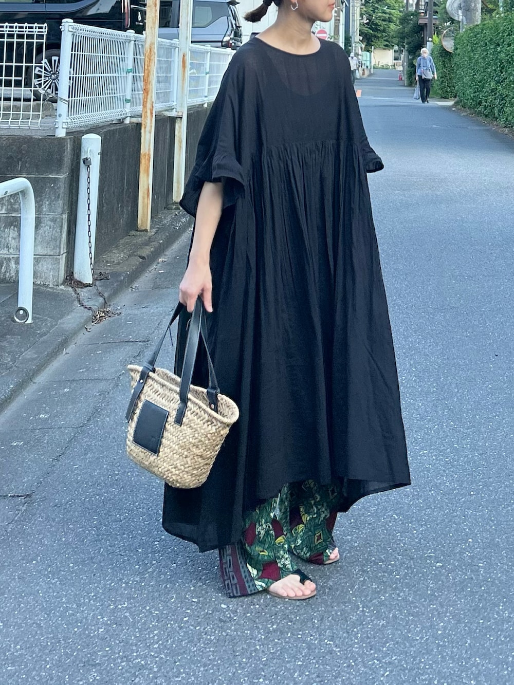 ブラック系のワンピース、ブラック系のかごバッグ、ブラック系のサンダルを着用したレディースの夏コーディネートの3枚目の写真