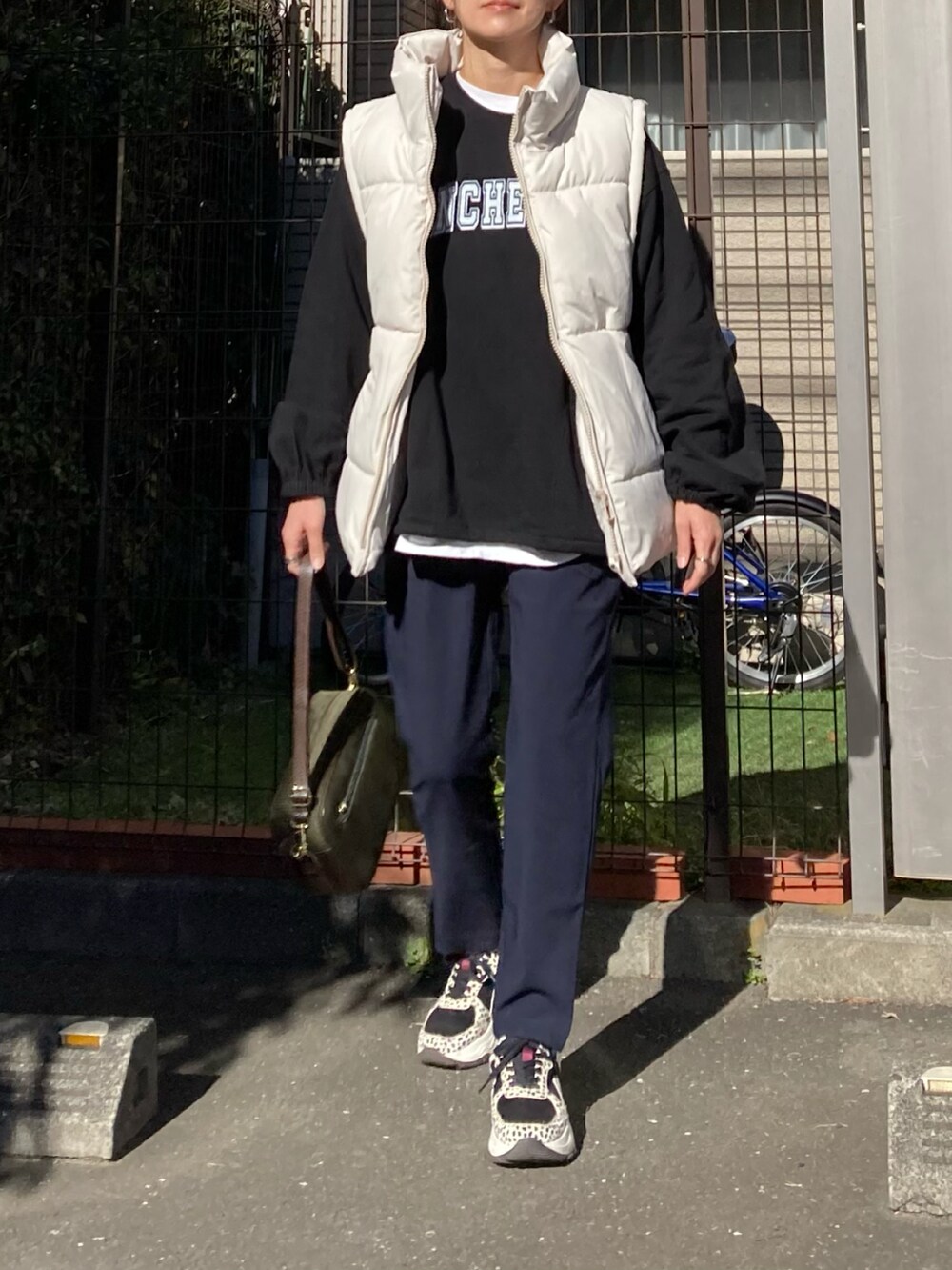 ベージュ系のダウンベスト、ブラック系のその他トップス、グリーン系のショルダーバッグを着用したレディースの冬コーディネートの2枚目の写真