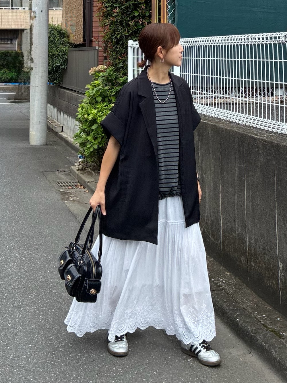 ブラック系のテーラードジャケット、グレー系のTシャツ/カットソー、ホワイト系のスカートを着用したレディースの秋コーディネートの4枚目の写真