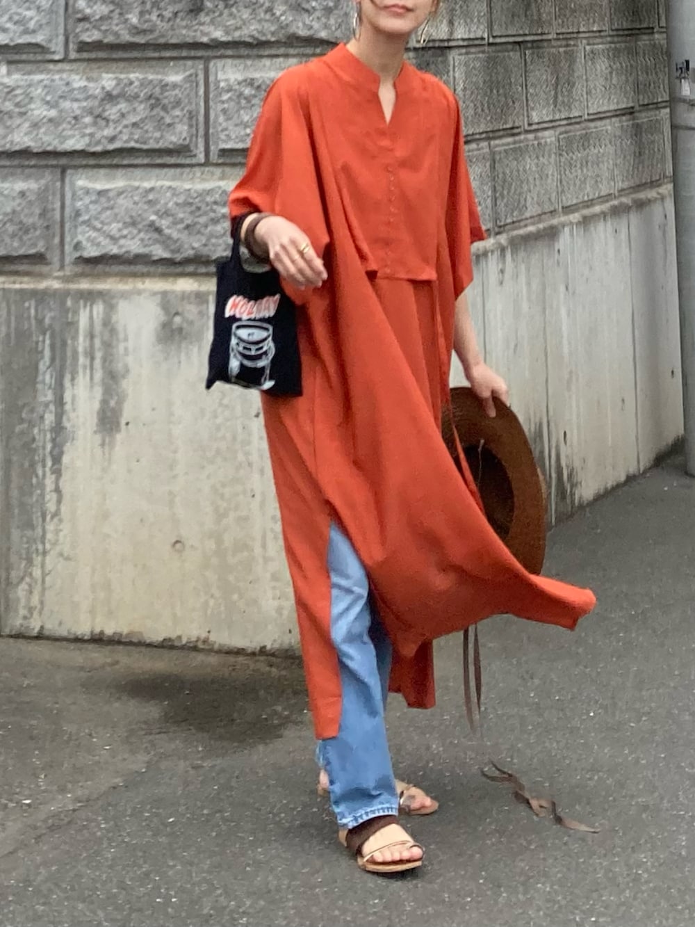 オレンジ系のシャツワンピースを着用したレディースの春コーディネートの2枚目の写真