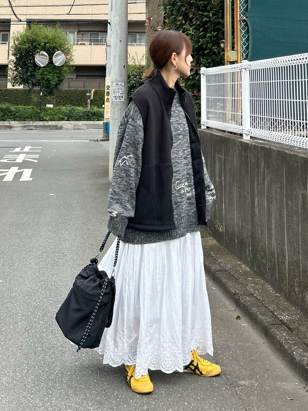 ブラック系のベスト、グレー系のニット/セーター、ブラック系のトートバッグを着用したレディースの秋コーディネートの3枚目の写真