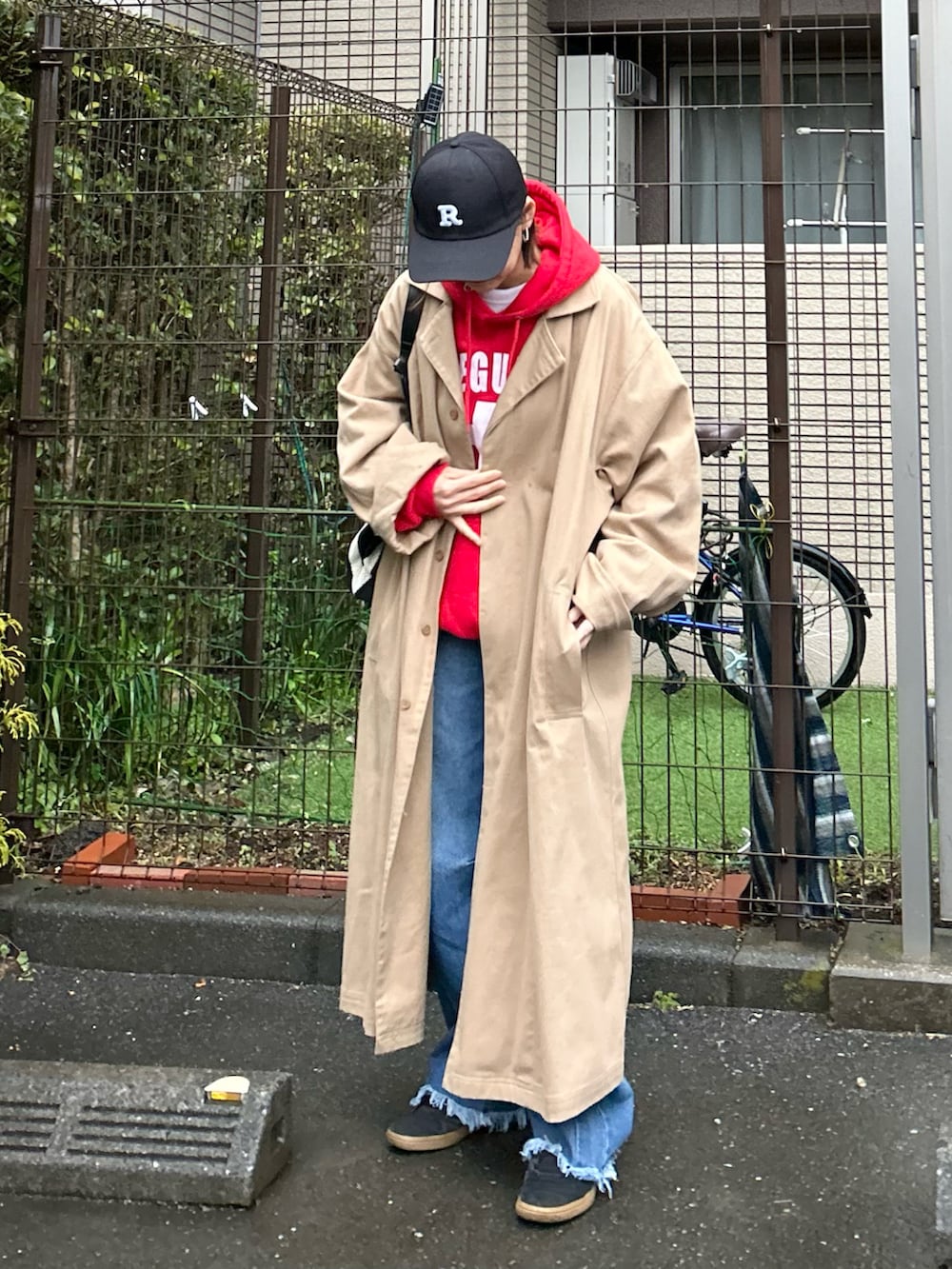 ブラック系のかごバッグ、ベージュ系のトレンチコート、ブルー系のデニムパンツを着用したレディースの春コーディネートの5枚目の写真