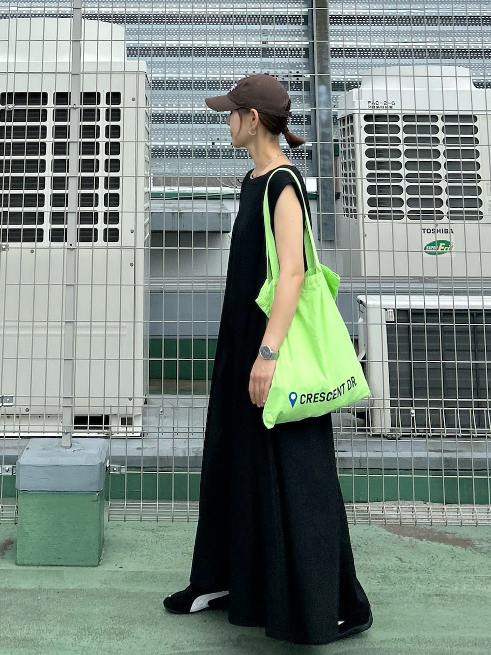 ブラック系のワンピース、グリーン系のトートバッグ、ブラック系のスニーカーを着用したレディースの夏コーディネートの4枚目の写真