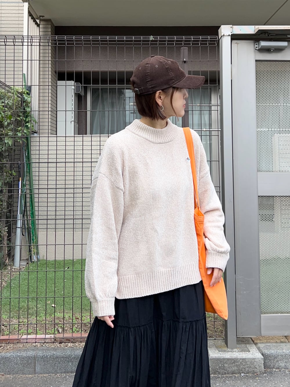 ベージュ系のニット/セーター、ブラック系のスカート、オレンジ系のトートバッグを着用したレディースの冬コーディネートの4枚目の写真