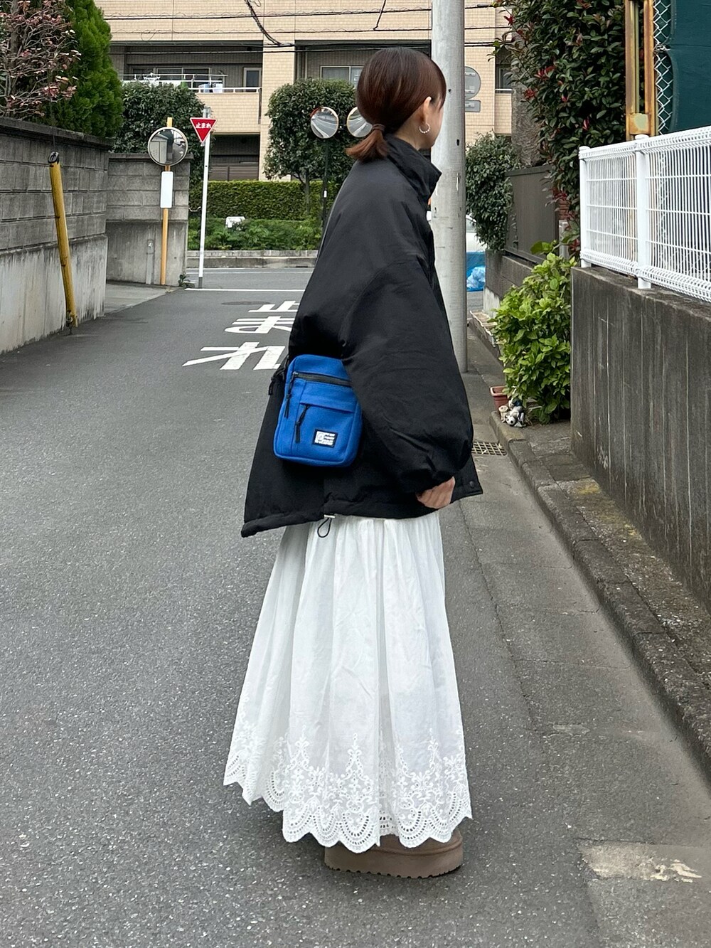 ブラック系のブルゾン、ベージュ系のブーツ、ホワイト系のスカートを着用したレディースの秋コーディネートの3枚目の写真