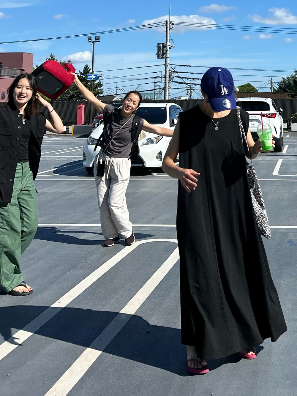 ブラック系のワンピース、パープル系のサンダル、ブルー系のキャップを着用したレディースの夏コーディネートの4枚目の写真