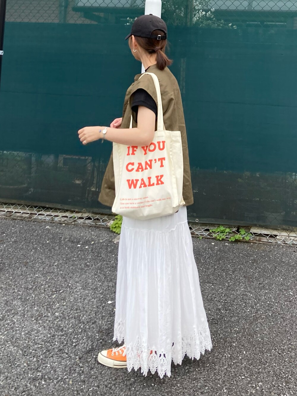 グリーン系のベスト、ブラック系のTシャツ/カットソー、ベージュ系のトートバッグを着用したレディースの夏コーディネートの4枚目の写真