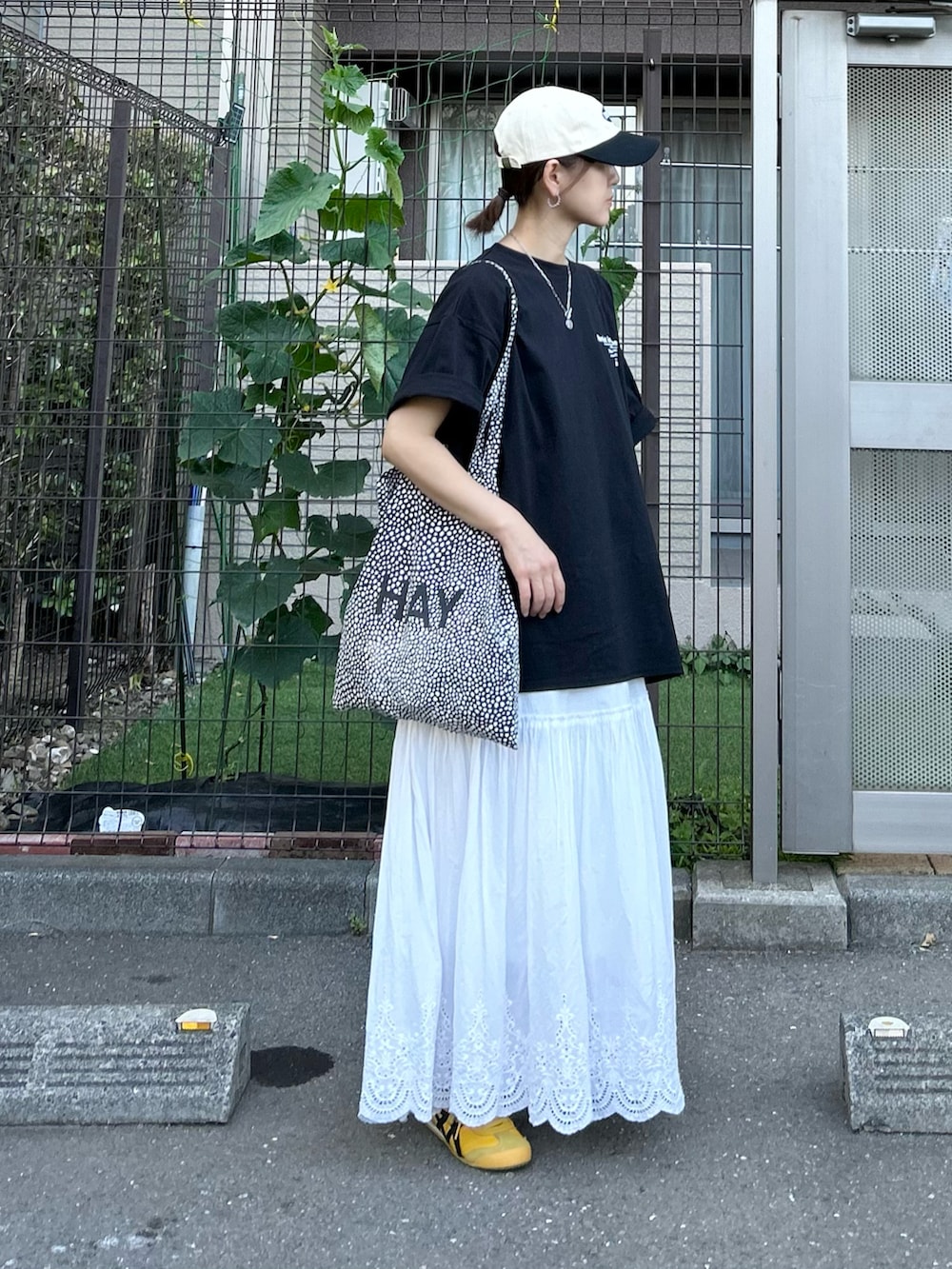 ブラック系のTシャツ/カットソー、ホワイト系のスカート、イエロー系のスニーカーを着用したレディースの夏コーディネートの3枚目の写真