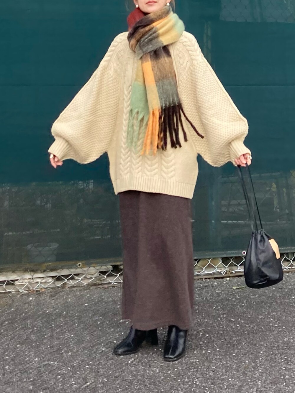 ホワイト系のニット/セーター、ブラウン系のスカート、ブラック系のハンドバッグを着用したレディースの冬コーディネートの2枚目の写真
