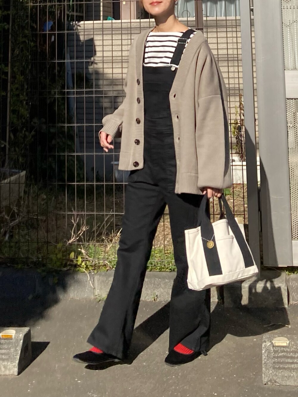 ベージュ系のカーディガン/ボレロ、ブラック系のサロペット/オーバーオール、ホワイト系のトートバッグを着用したレディースの冬コーディネートの2枚目の写真
