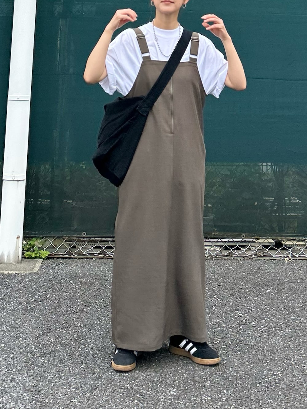 ベージュ系のワンピース、ホワイト系のTシャツ/カットソー、ブラック系のショルダーバッグを着用したレディースの春コーディネートの2枚目の写真