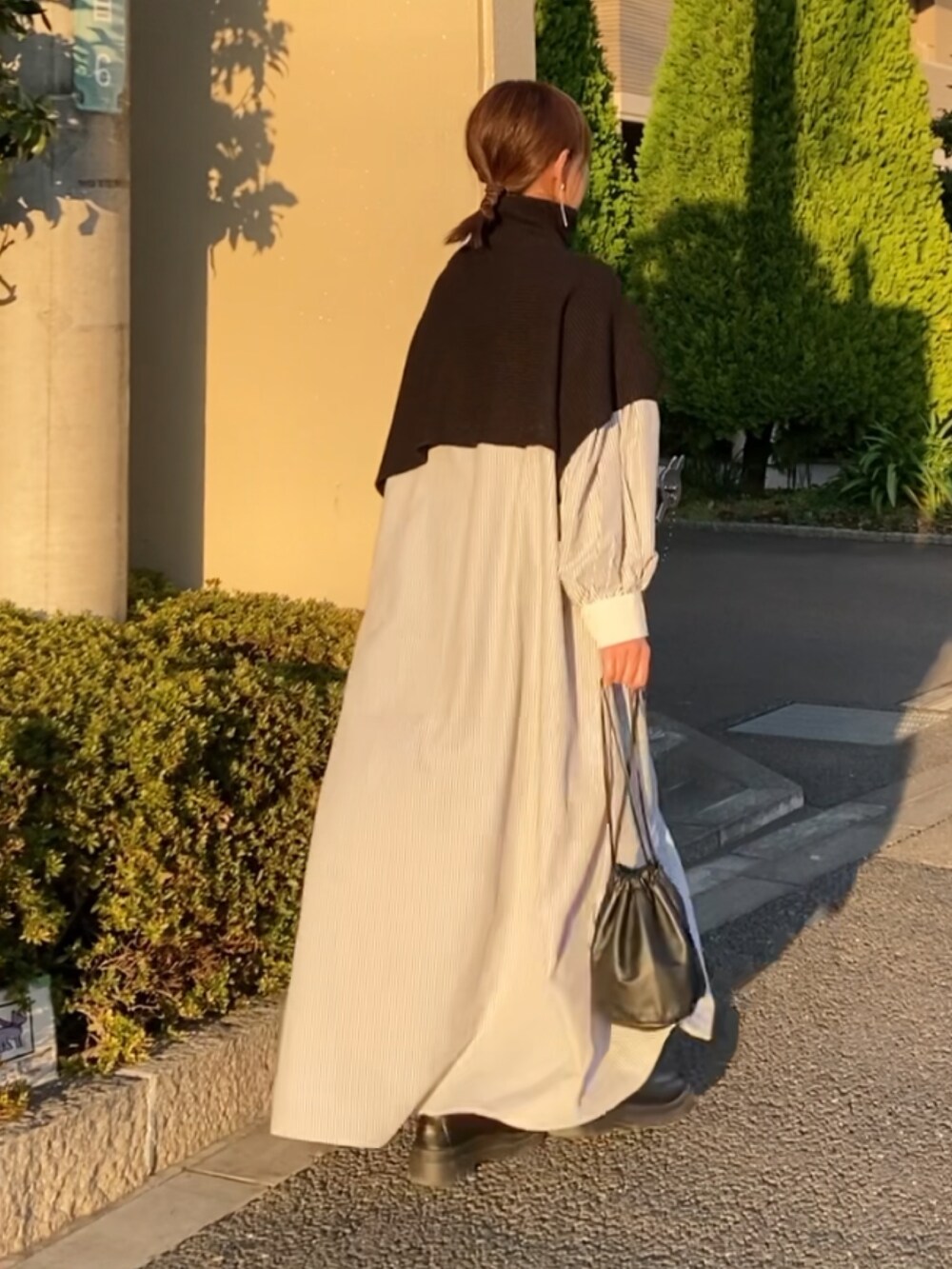 ブラック系のベスト、ブラック系のワンピース、ブラック系のブーツを着用したレディースの秋コーディネートの2枚目の写真