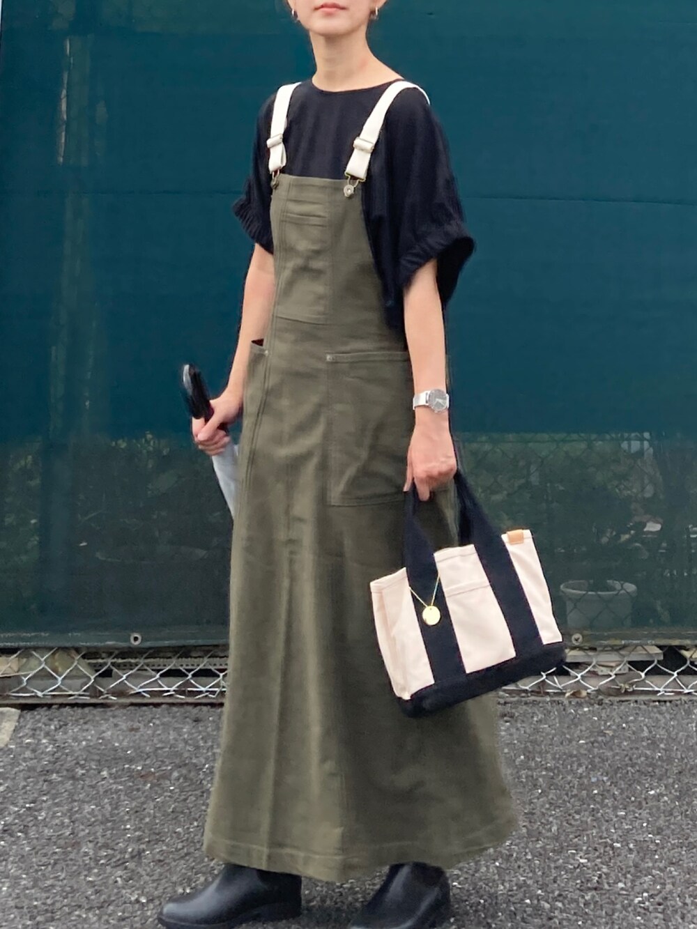 ブラック系のTシャツ/カットソー、グリーン系のジャンパースカート、ホワイト系のトートバッグを着用したレディースの秋コーディネートの4枚目の写真