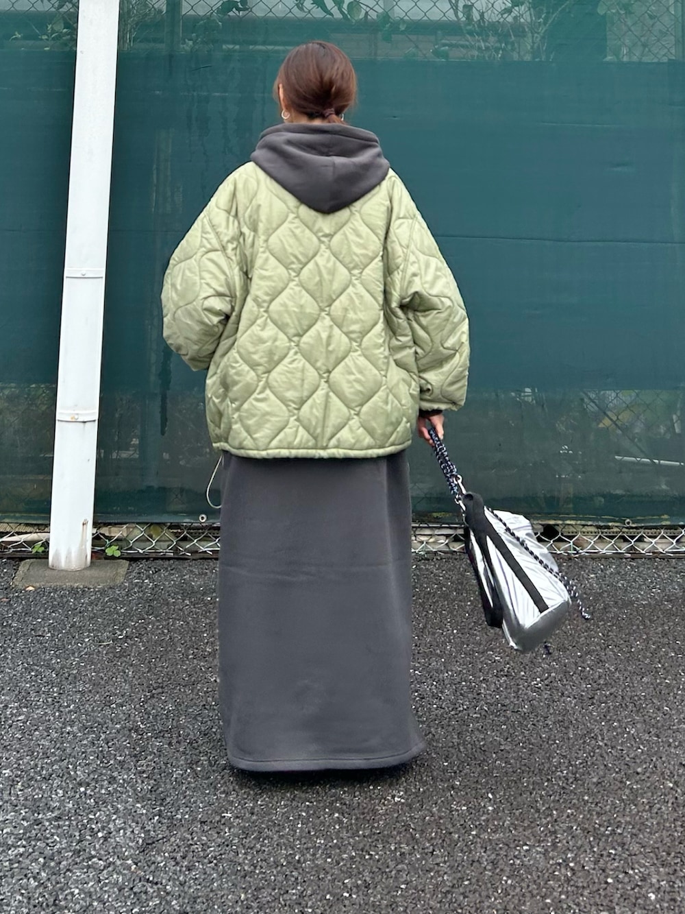 グレー系のワンピース、グリーン系のノーカラージャケット、シルバー系のトートバッグを着用したレディースの秋コーディネートの5枚目の写真