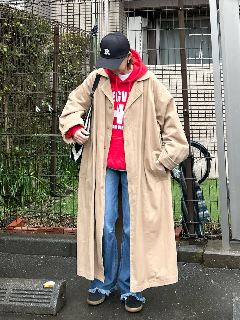 ブラック系のかごバッグ、ベージュ系のトレンチコート、ブルー系のデニムパンツを着用したレディースの春コーディネートの4枚目の写真