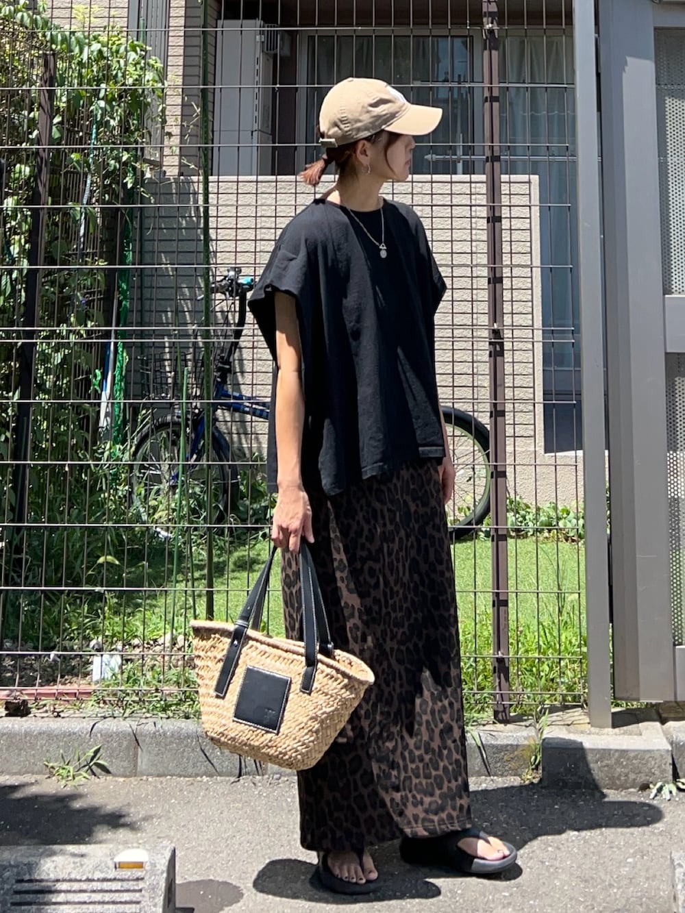 ブラック系のTシャツ/カットソー、ブラック系のかごバッグ、ブラウン系のスカートを着用したレディースの夏コーディネートの2枚目の写真