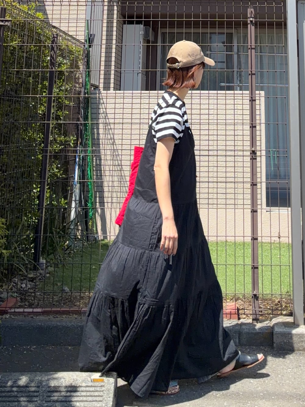 ブラック系のワンピース、ブラック系のTシャツ/カットソー、レッド系のトートバッグを着用したレディースの春コーディネートの2枚目の写真