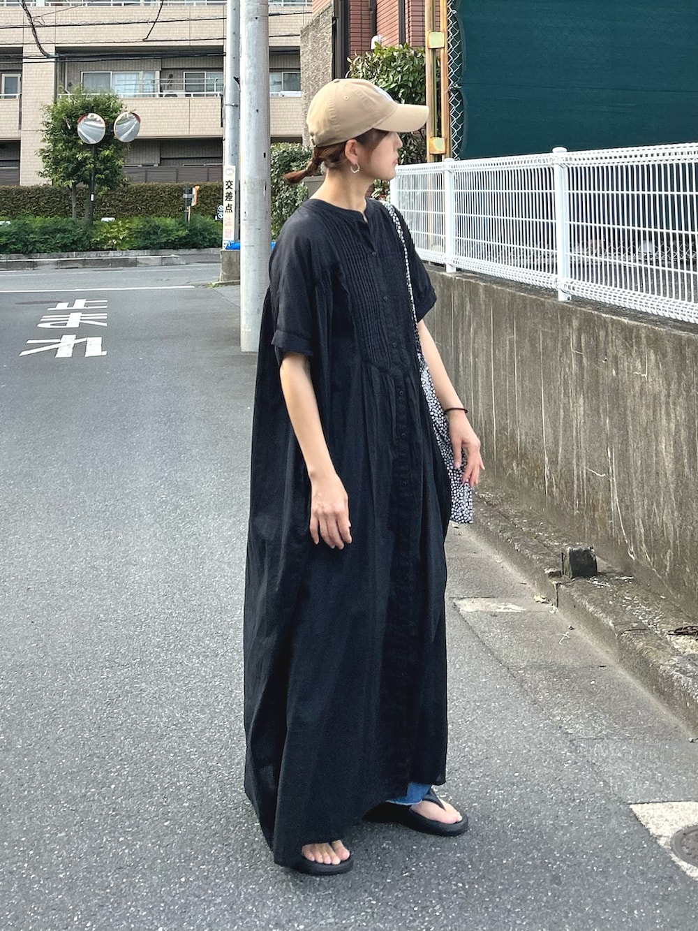 ブルー系のデニムパンツ、ブラック系のワンピース、ベージュ系のキャップを着用したレディースの夏コーディネートの3枚目の写真