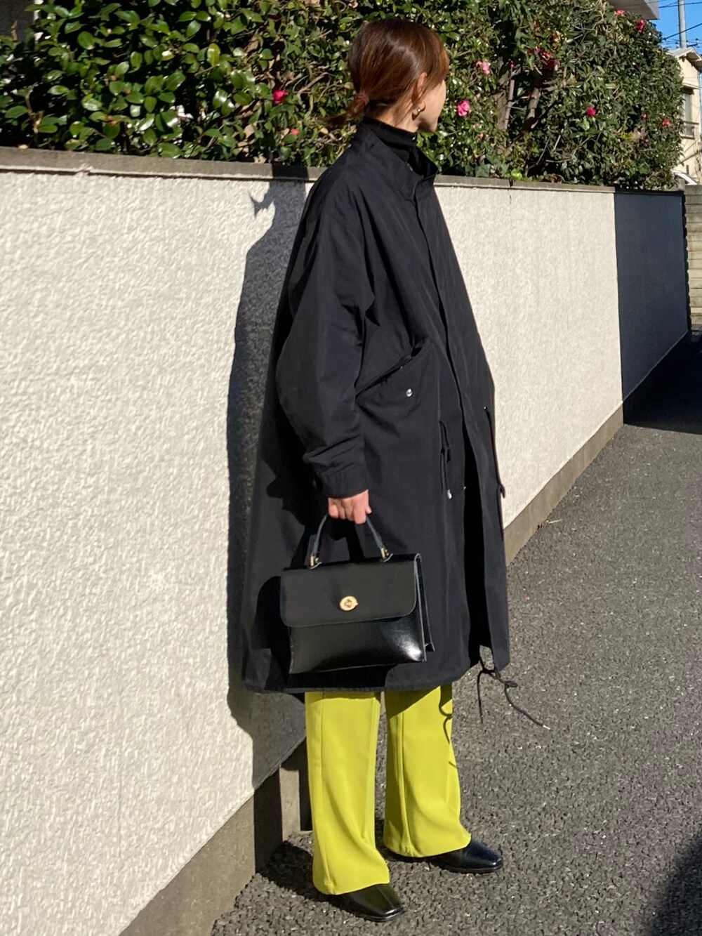 ブラック系のモッズコート、グリーン系のスラックス、ブラック系のショルダーバッグを着用したレディースの冬コーディネートの2枚目の写真