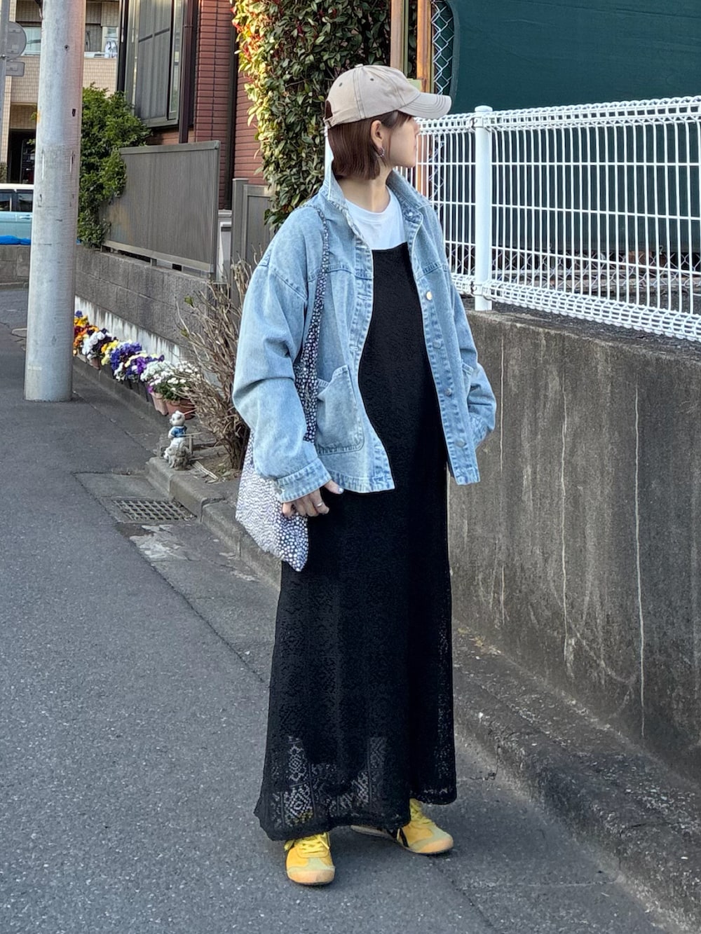 ブルー系のデニムジャケット、ブラック系のワンピース、イエロー系のスニーカーを着用したレディースの春コーディネートの3枚目の写真