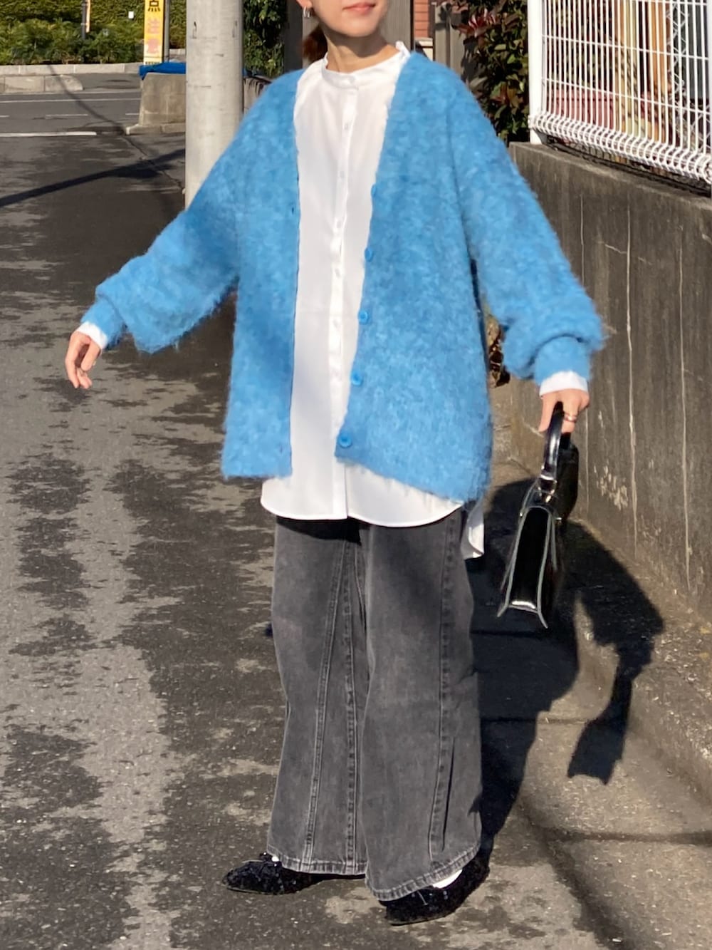 ブルー系のカーディガン/ボレロ、ホワイト系のシャツ/ブラウス、ブラック系のデニムパンツを着用したレディースの冬コーディネートの4枚目の写真