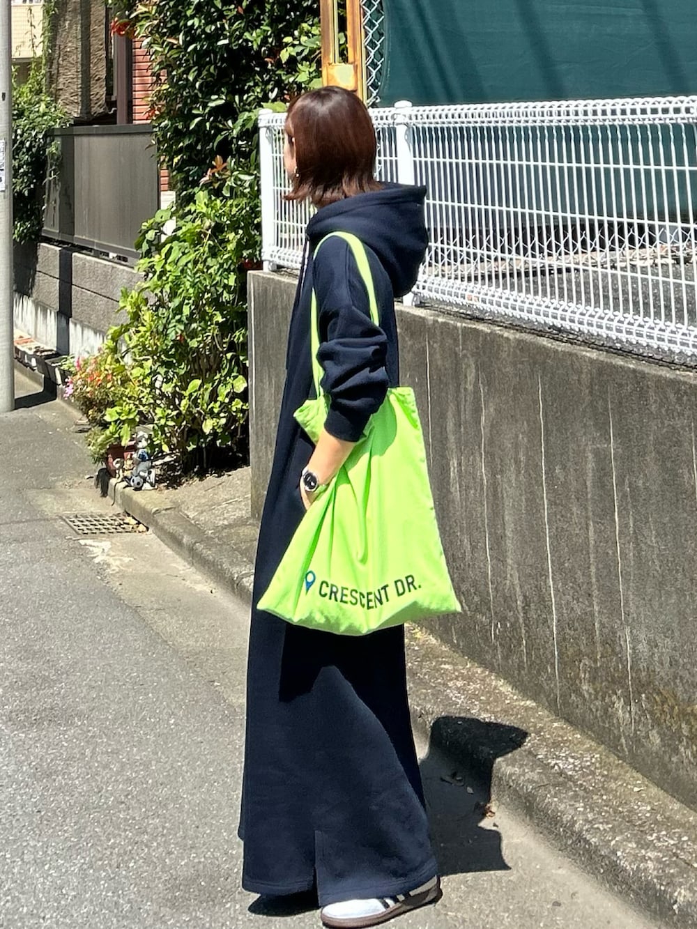 ブルー系のワンピース、グリーン系のトートバッグ、シルバー系のスニーカーを着用したレディースの秋コーディネートの3枚目の写真