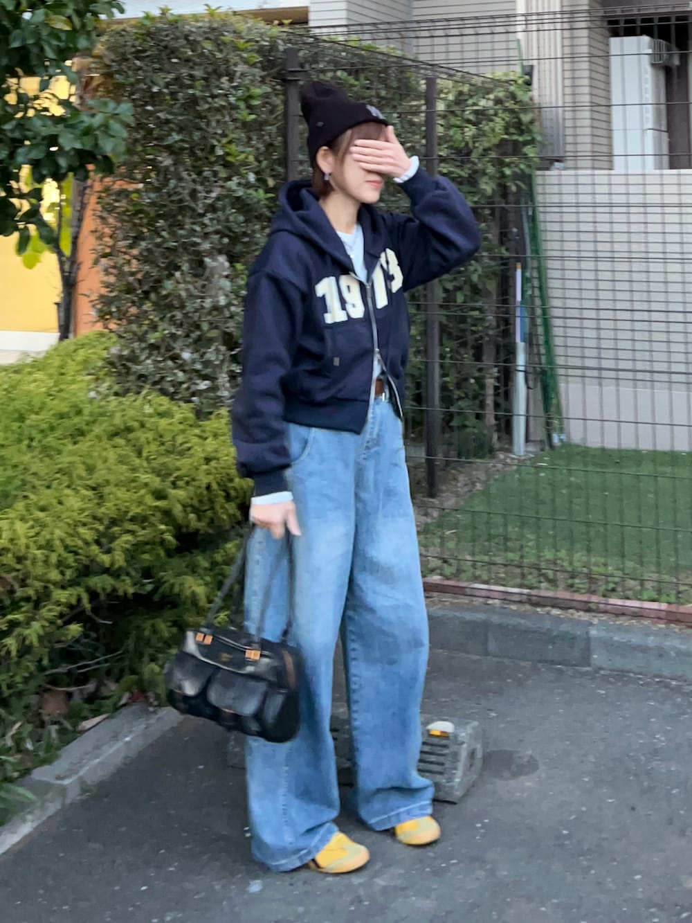 ブルー系のパーカー、ブラック系のハンドバッグ、イエロー系のスニーカーを着用したレディースの冬コーディネートの2枚目の写真