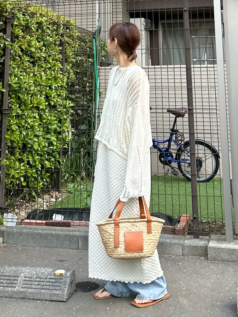 ホワイト系のワンピース、ブラウン系のかごバッグ、ブルー系のデニムパンツを着用したレディースの春コーディネートの2枚目の写真