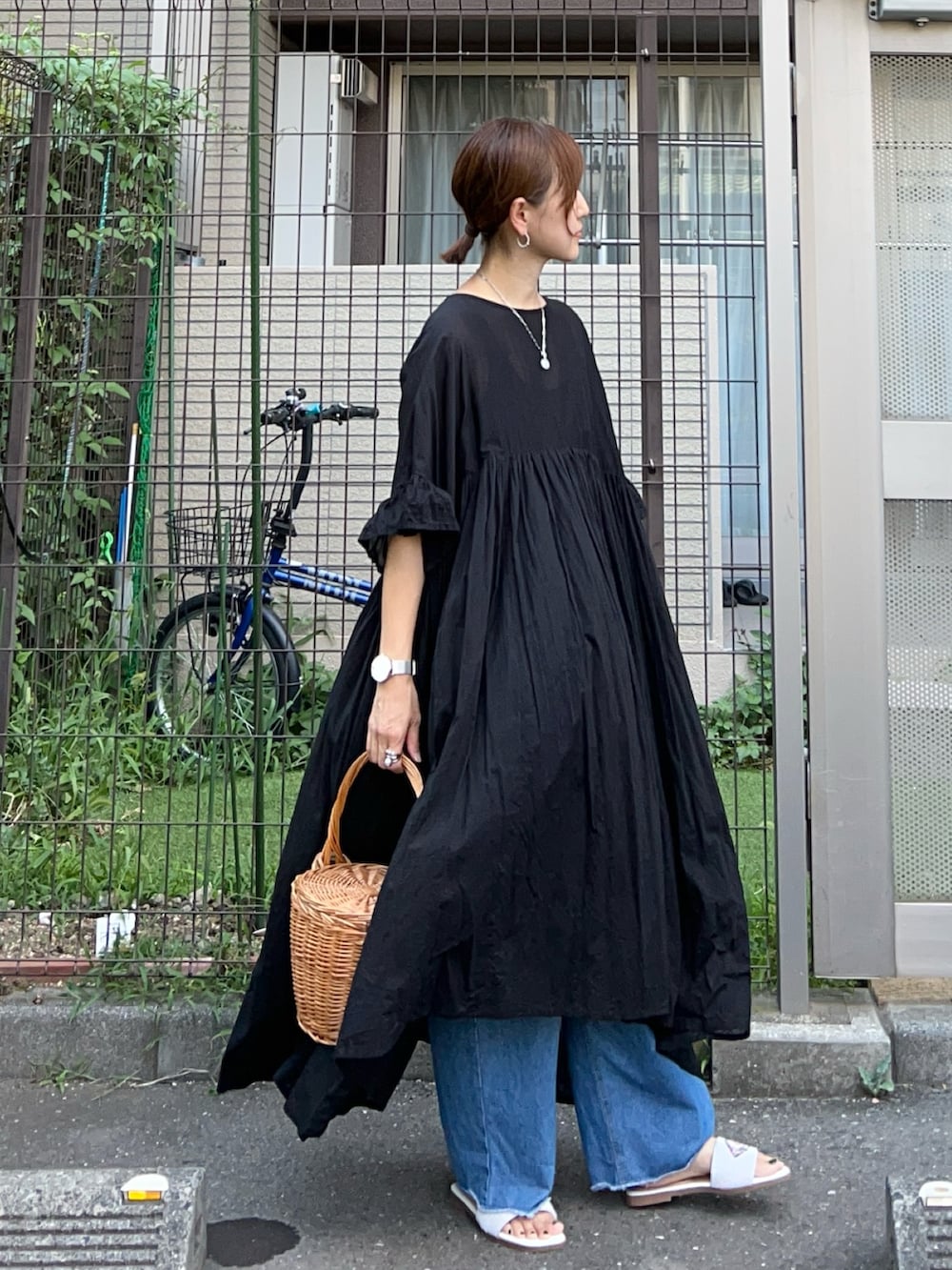ブラック系のワンピース、ブルー系のデニムパンツ、ホワイト系のサンダルを着用したレディースの夏コーディネートの3枚目の写真