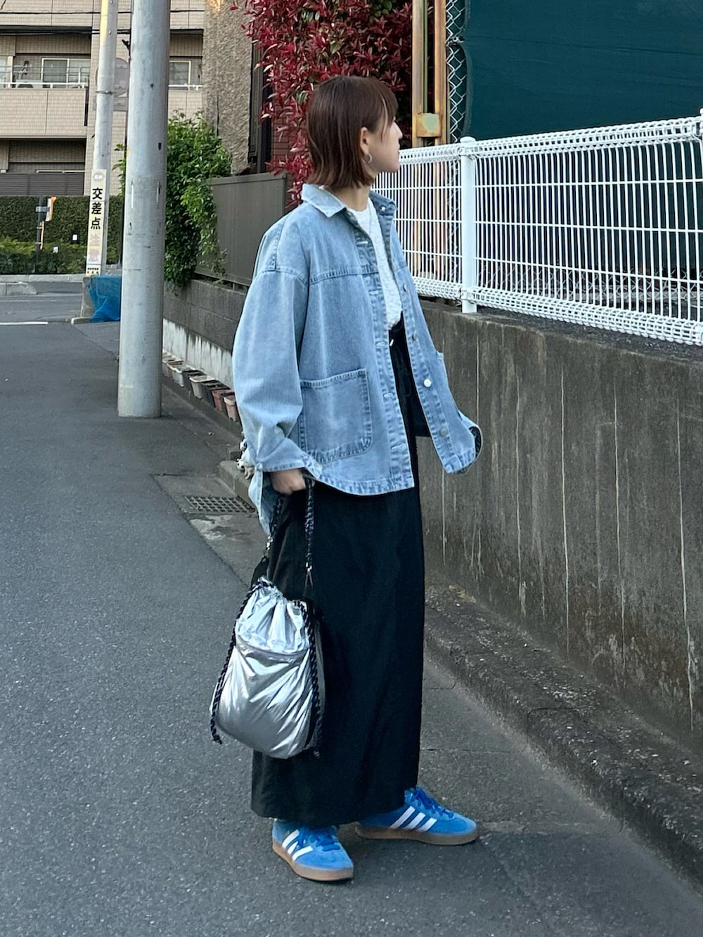 ブルー系のデニムジャケット、ブラック系のジャンパースカート、シルバー系のショルダーバッグを着用したレディースの春コーディネートの2枚目の写真