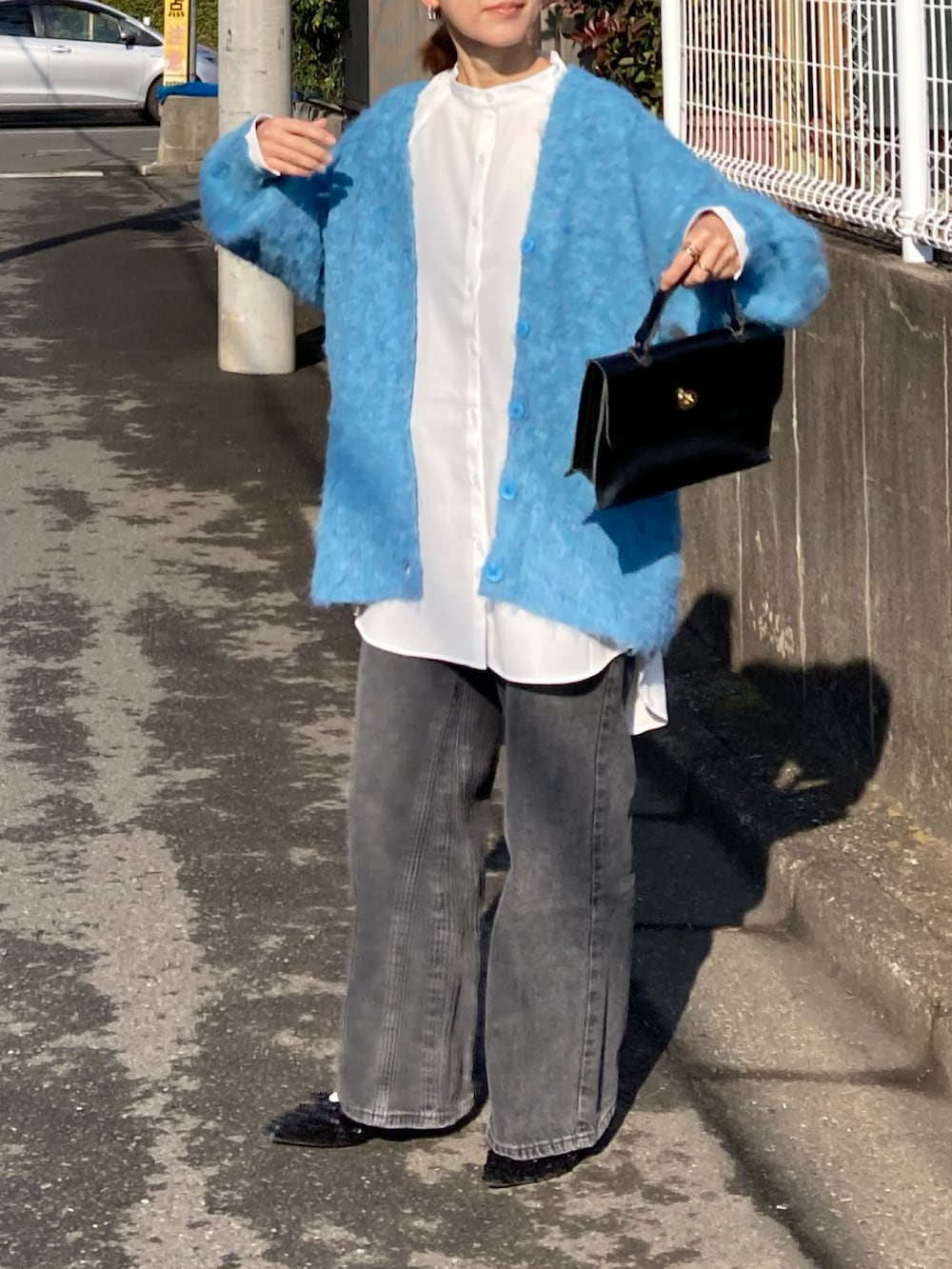 ブルー系のカーディガン/ボレロ、ホワイト系のシャツ/ブラウス、ブラック系のデニムパンツを着用したレディースの冬コーディネートの5枚目の写真