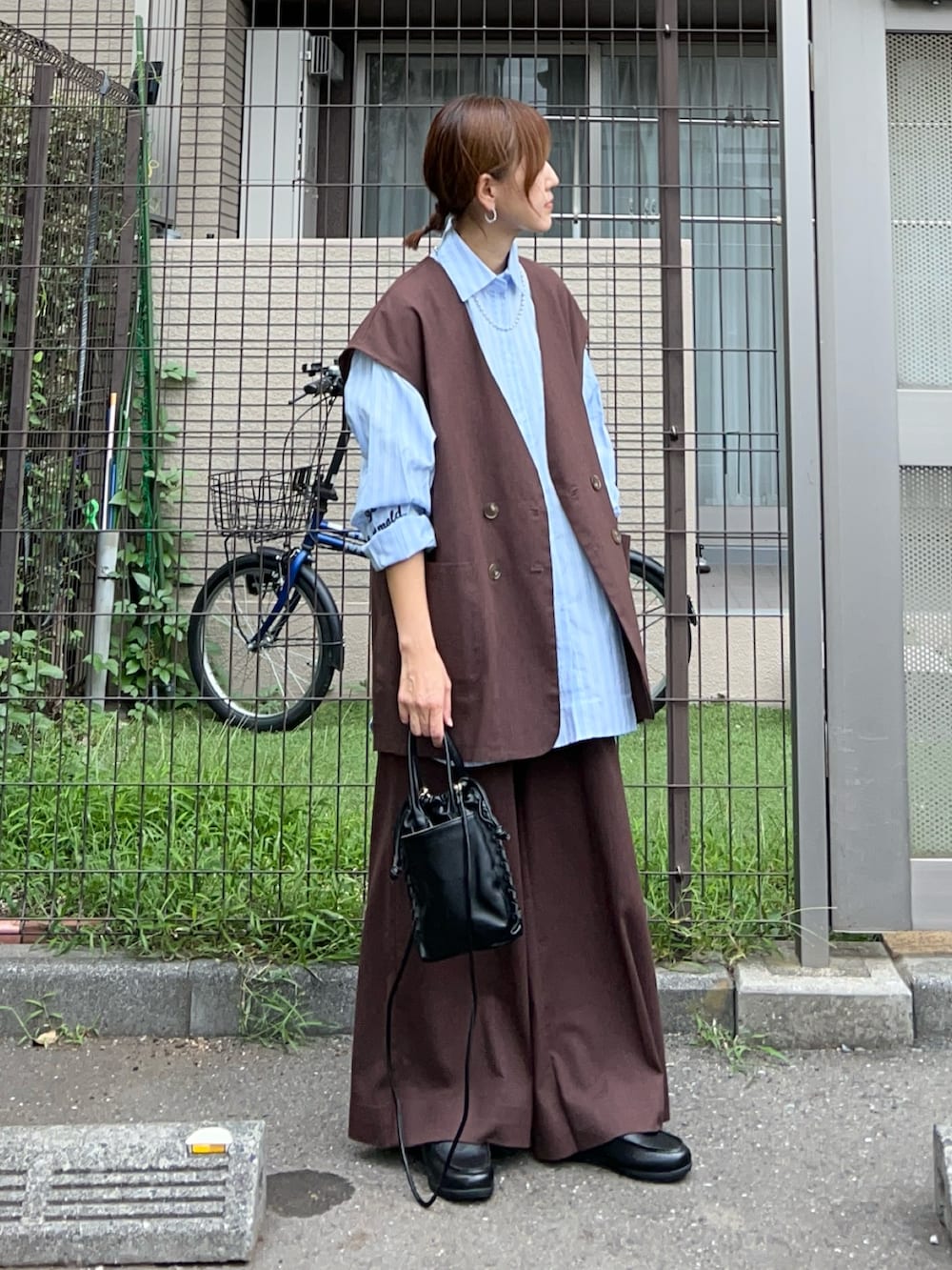 ブラウン系のベスト、ブラウン系のスラックス、ブルー系のシャツ/ブラウスを着用したレディースの秋コーディネートの2枚目の写真