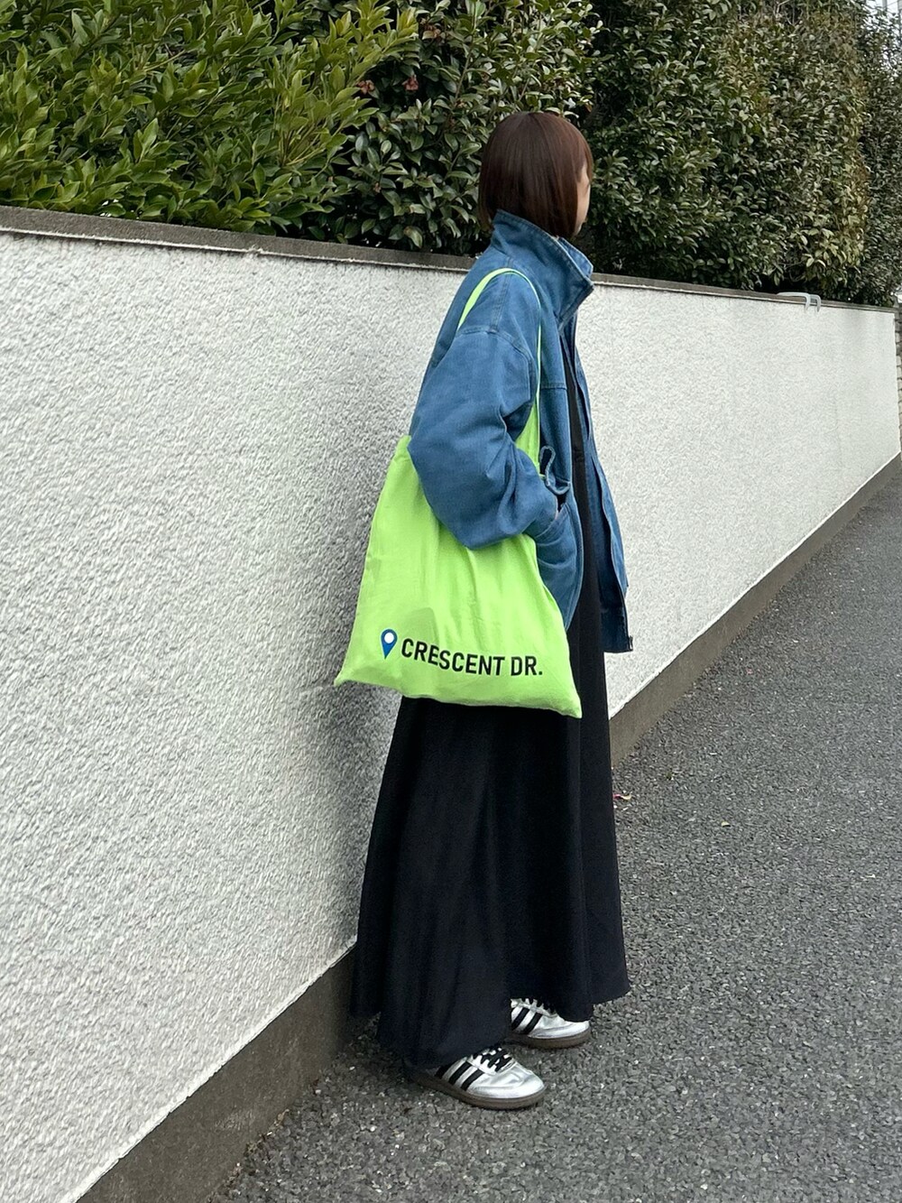 ブルー系のデニムジャケット、ブラック系のワンピース、グリーン系のトートバッグを着用したレディースの春コーディネートの4枚目の写真