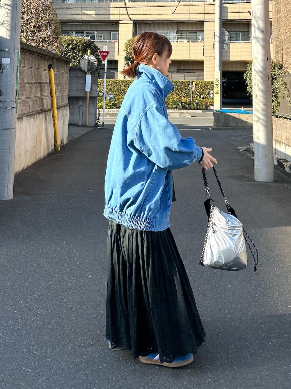 ブルー系のデニムジャケット、ブラック系のスカート、シルバー系のショルダーバッグを着用したレディースの春コーディネートの4枚目の写真