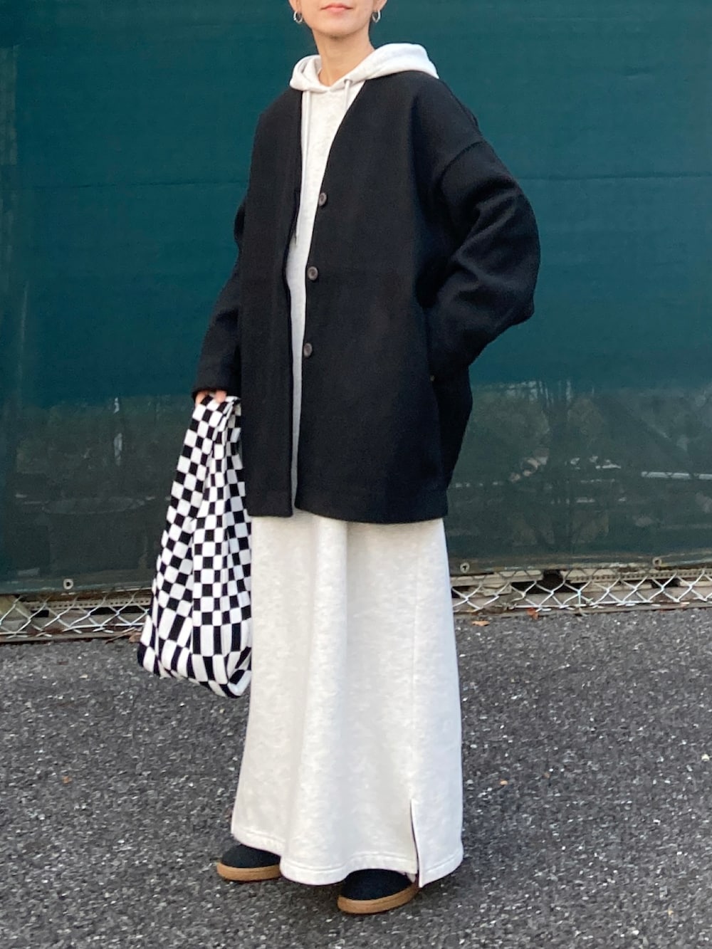 ブラック系のノーカラーコート、グレー系のワンピース、ブラック系のスニーカーを着用したレディースの冬コーディネートの3枚目の写真