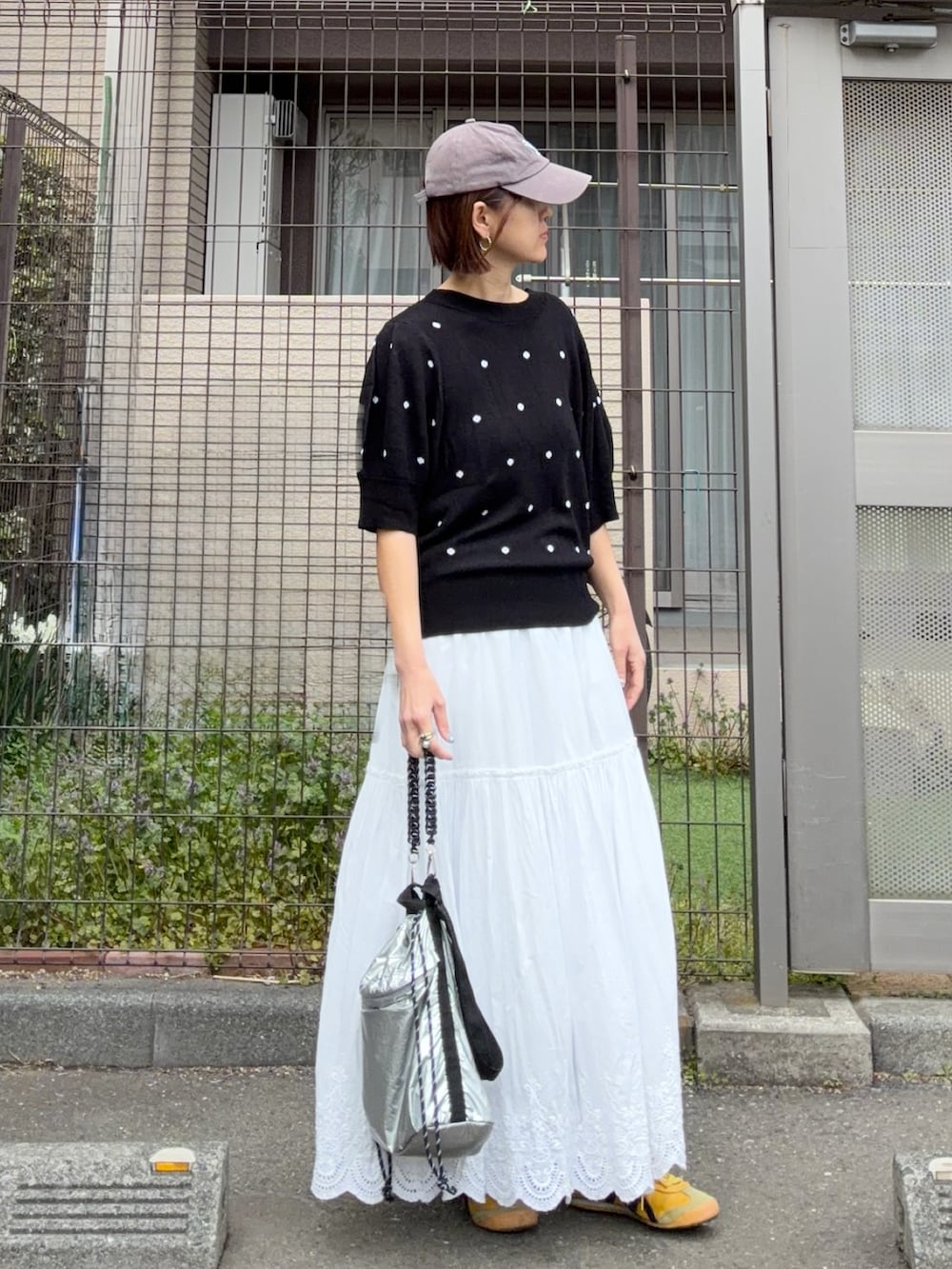 ブラック系のニット/セーター、ホワイト系のスカート、シルバー系のトートバッグを着用したレディースの春コーディネートの3枚目の写真