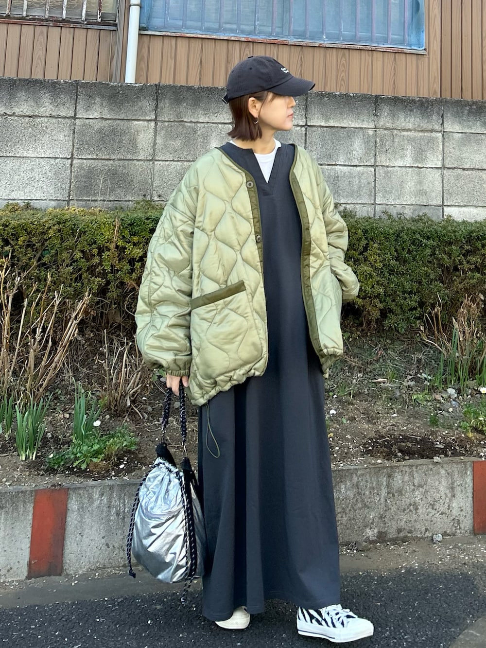 グリーン系のブルゾン、シルバー系のトートバッグ、グレー系のワンピースを着用したレディースの冬コーディネートの4枚目の写真