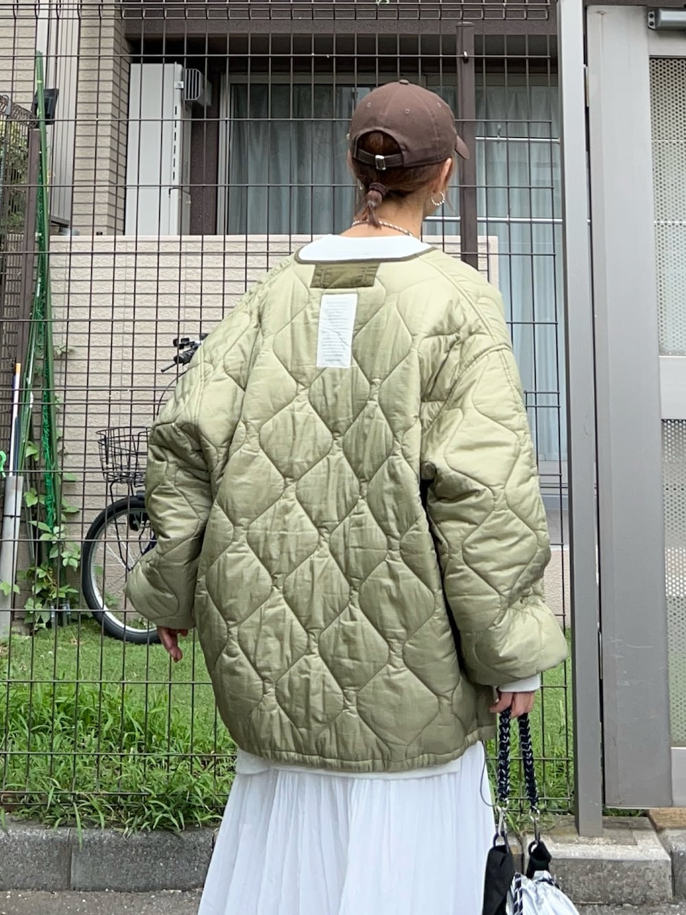 ホワイト系のスカート、シルバー系のトートバッグ、グリーン系のスニーカーを着用したレディースの秋コーディネートの5枚目の写真