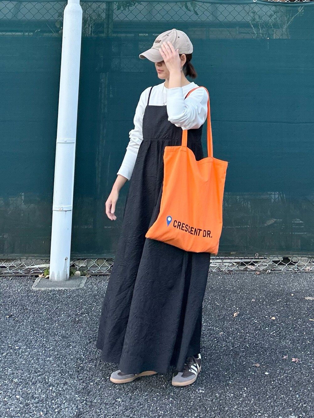 ブラック系のワンピース、オレンジ系のトートバッグを着用したレディースの冬コーディネートの5枚目の写真