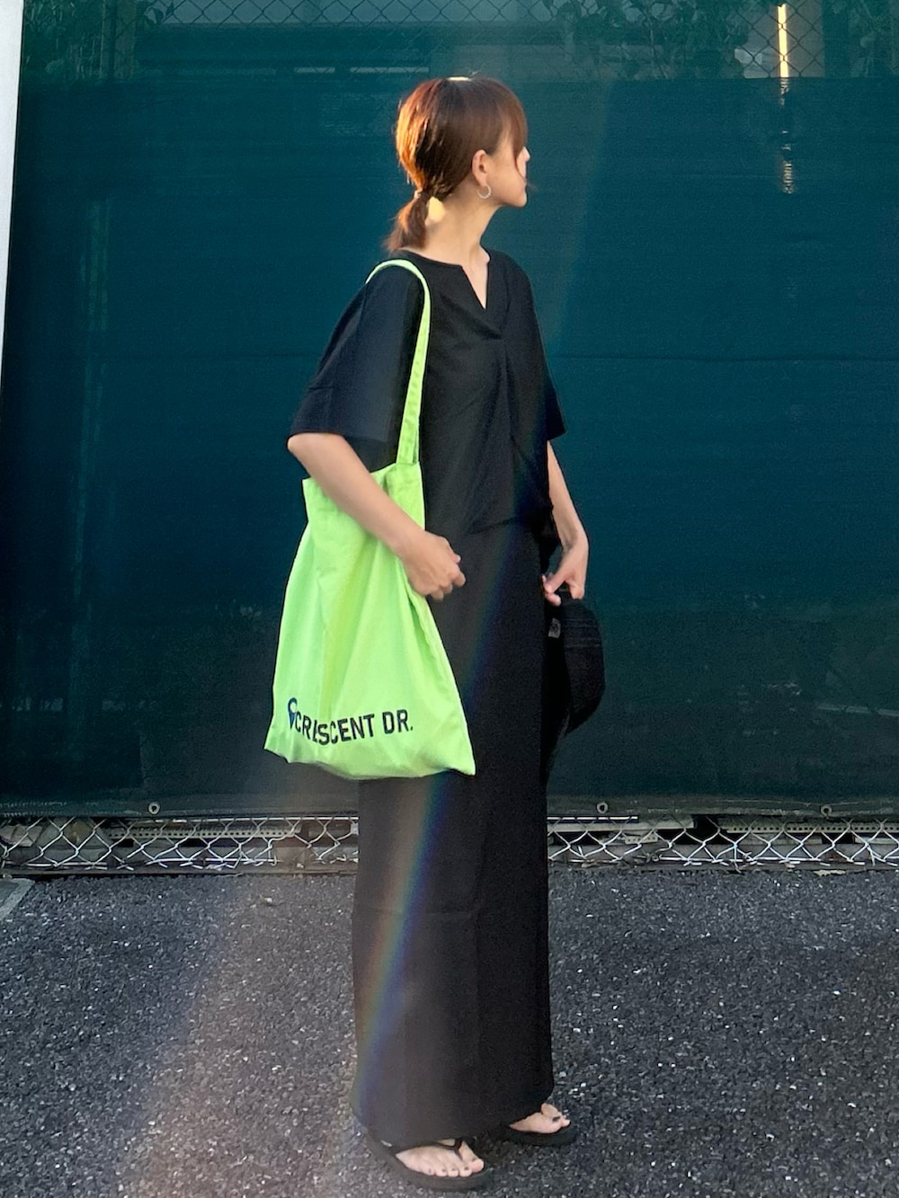 ブラック系のTシャツ/カットソー、ブラック系のスカート、グリーン系のトートバッグを着用したレディースの夏コーディネートの3枚目の写真