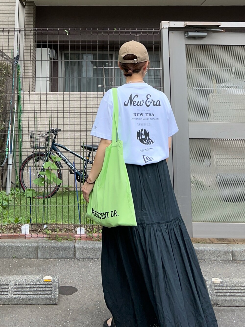 ブラック系のスカート、グリーン系のトートバッグ、ホワイト系のTシャツ/カットソーを着用したレディースの夏コーディネートの3枚目の写真