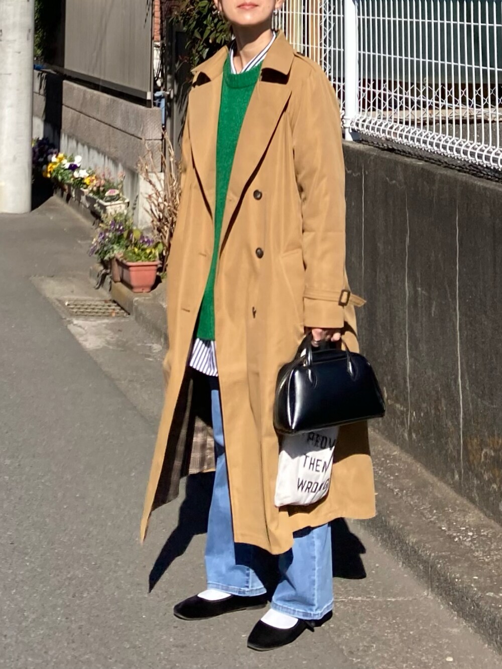 イエロー系のトレンチコートを着用したレディースの冬コーディネートの3枚目の写真