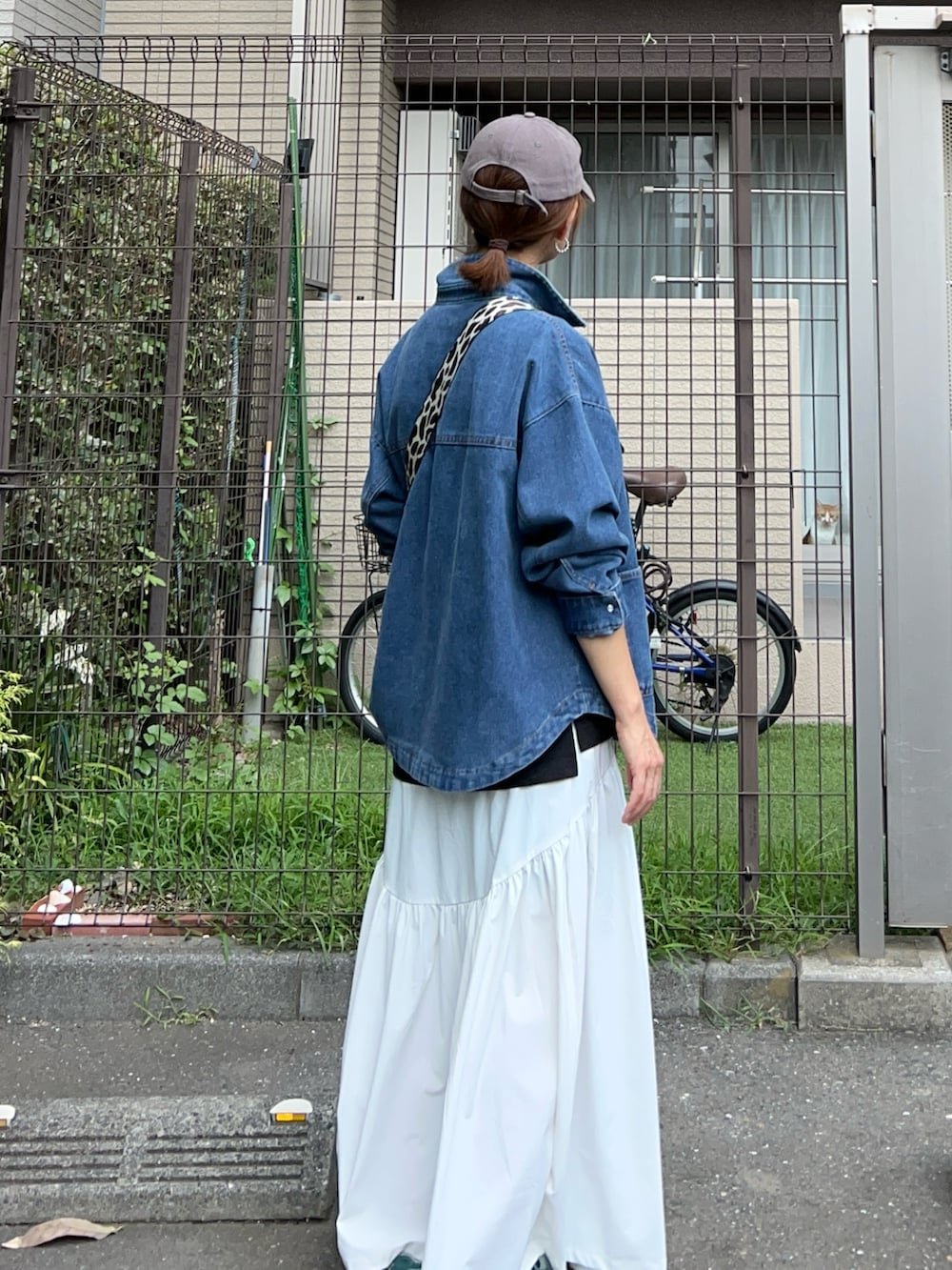 ブルー系のデニムジャケット、ブラック系のボディバッグ/ウエストポーチ、グリーン系のスニーカーを着用したレディースの秋コーディネートの5枚目の写真