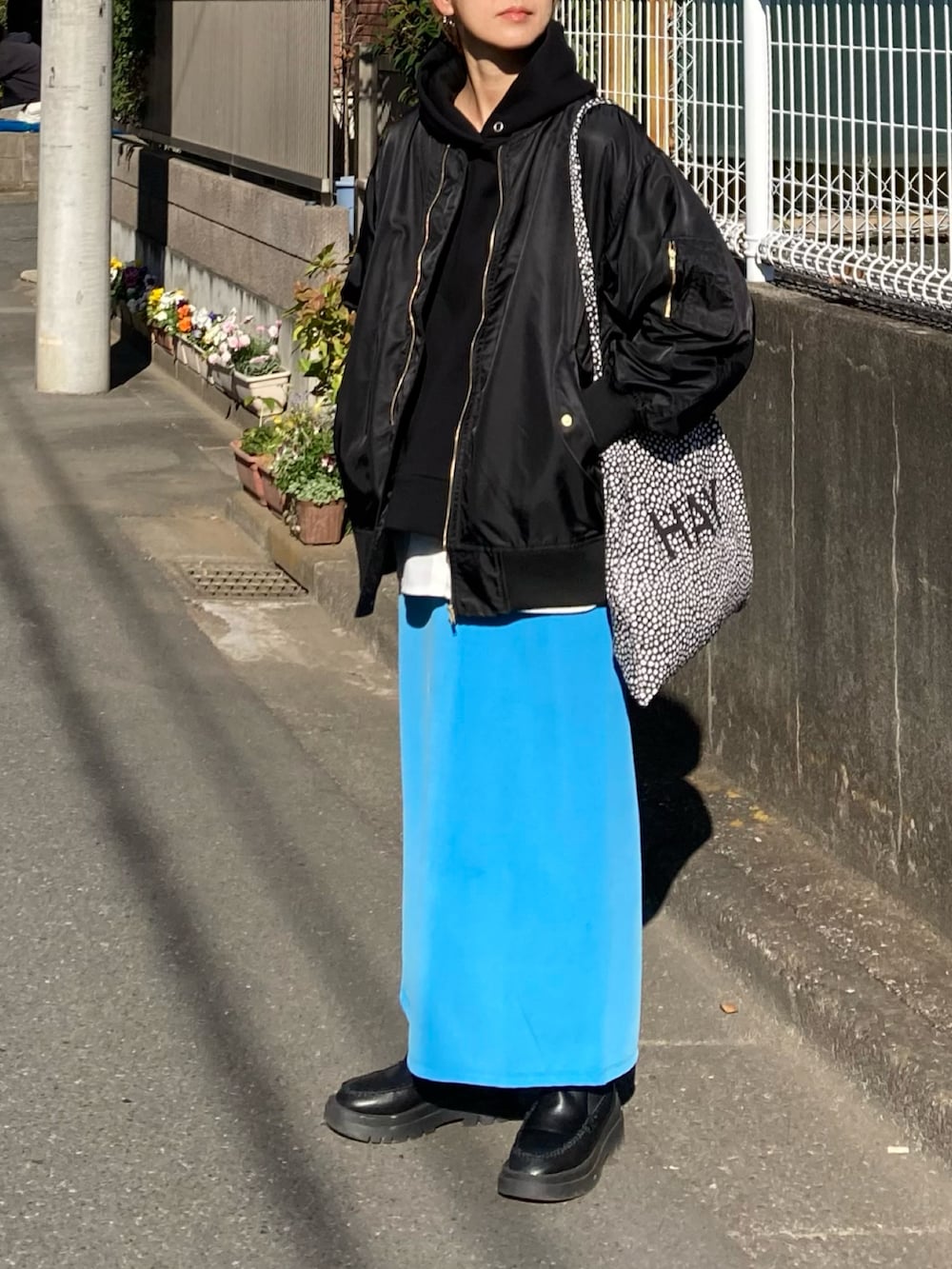 ブラック系のブルゾン、ブラック系のパーカー、ブルー系のスカートを着用したレディースの冬コーディネートの2枚目の写真