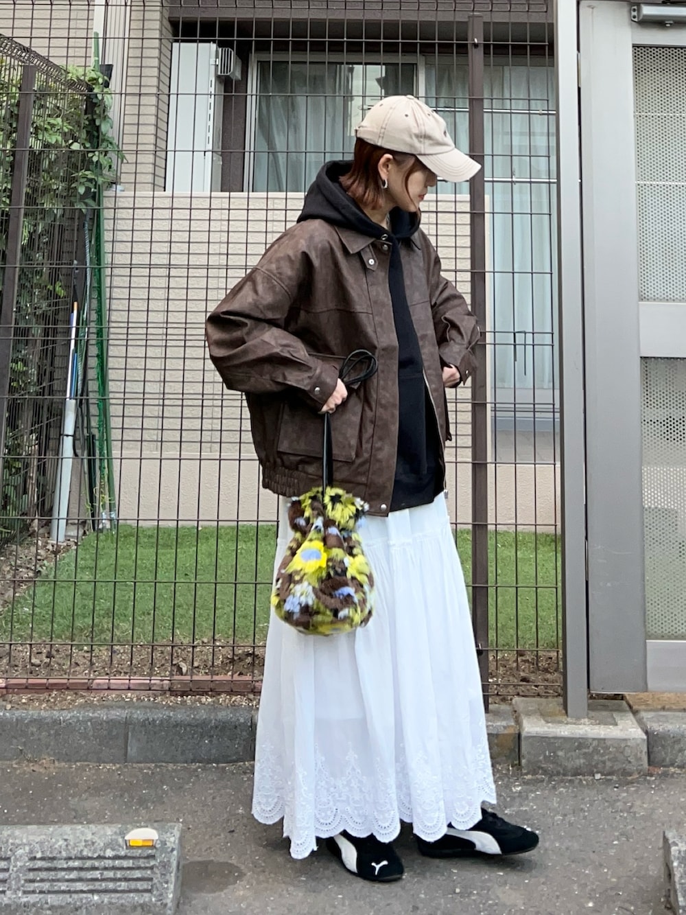 ブラウン系のブルゾン、グリーン系のハンドバッグ、ブラック系のパーカーを着用したレディースの秋コーディネートの2枚目の写真