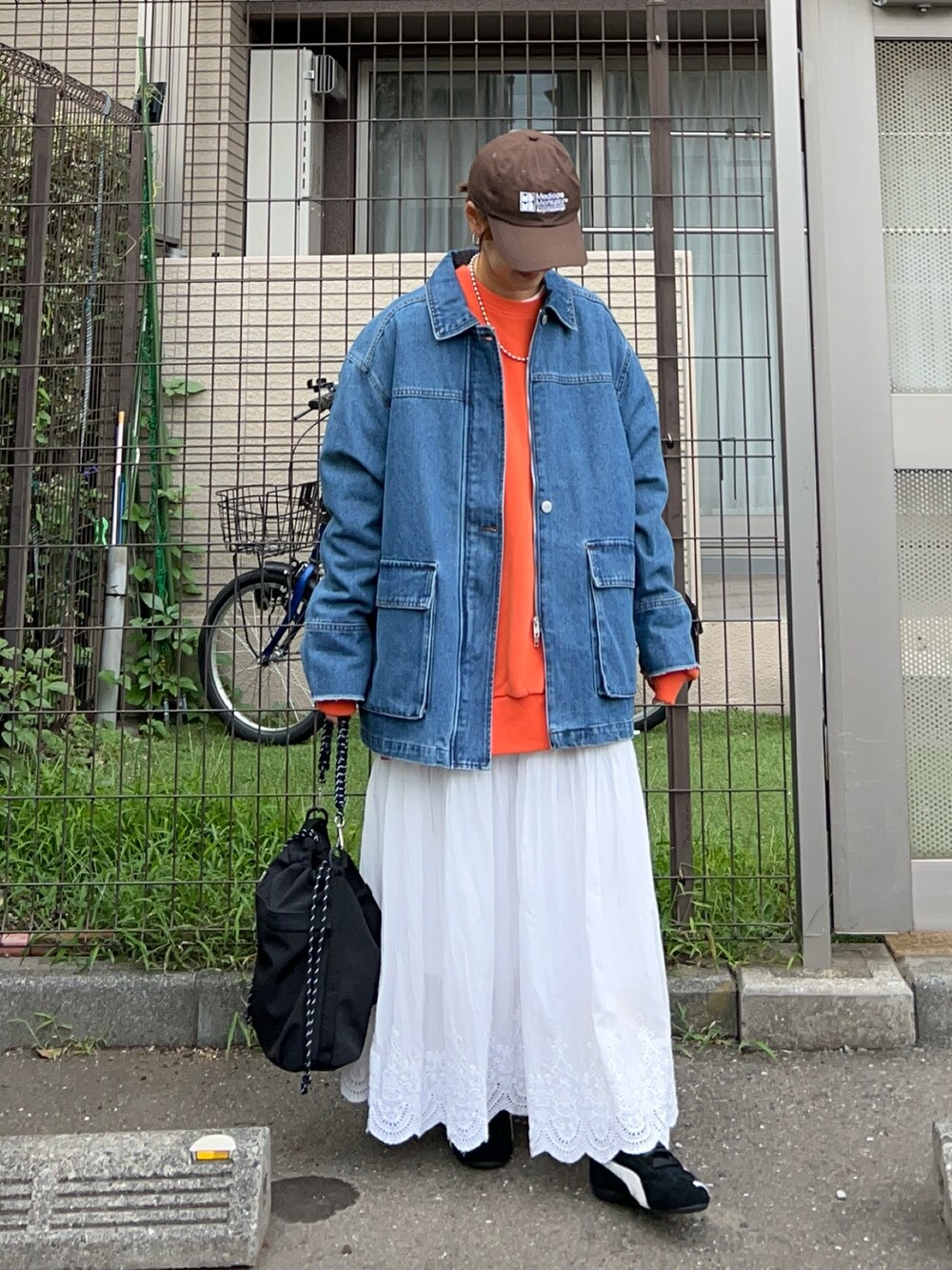 ブルー系のデニムジャケット、オレンジ系のスウェット、ブラック系のショルダーバッグを着用したレディースの秋コーディネートの3枚目の写真