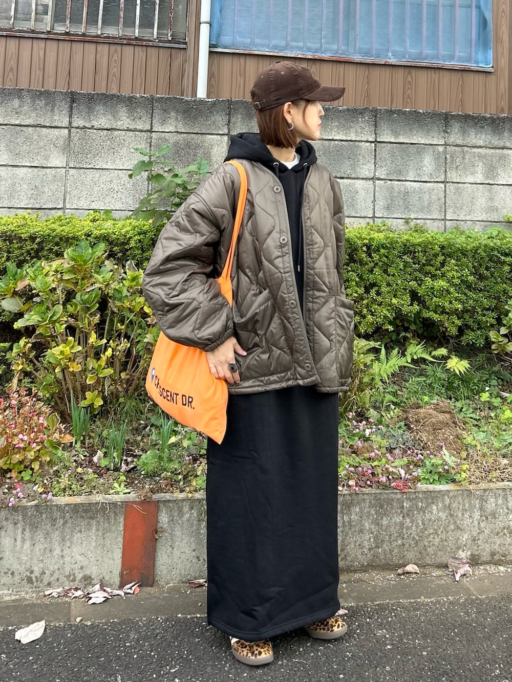 ブラウン系のブルゾン、ブラック系のワンピース、オレンジ系のトートバッグを着用したレディースの冬コーディネートの4枚目の写真