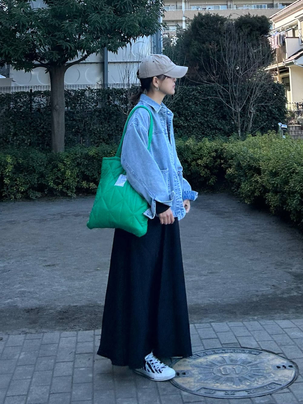 ブルー系のデニムジャケット、ブラック系のワンピース、グリーン系のトートバッグを着用したレディースの春コーディネートの3枚目の写真