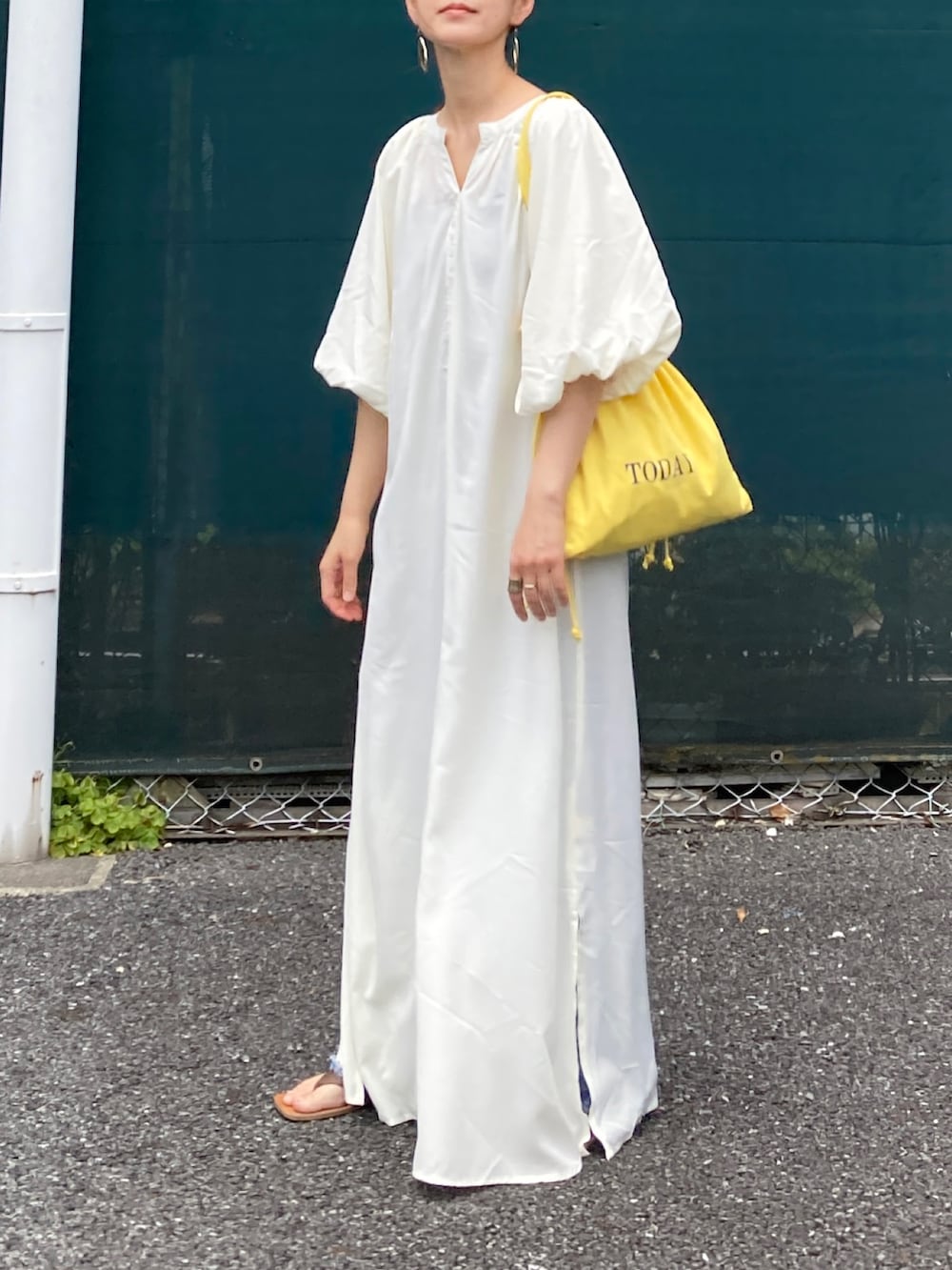 ホワイト系のワンピース、イエロー系のトートバッグ、ブルー系のデニムパンツを着用したレディースの夏コーディネートの3枚目の写真